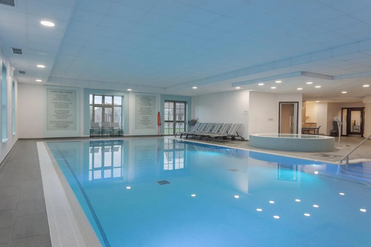 a large swimming pool with a tub in a building at Cambridge Belfry Hotel & Spa in Cambourne