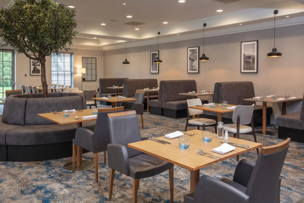 a restaurant with tables and couches and chairs at Cambridge Belfry Hotel & Spa in Cambourne