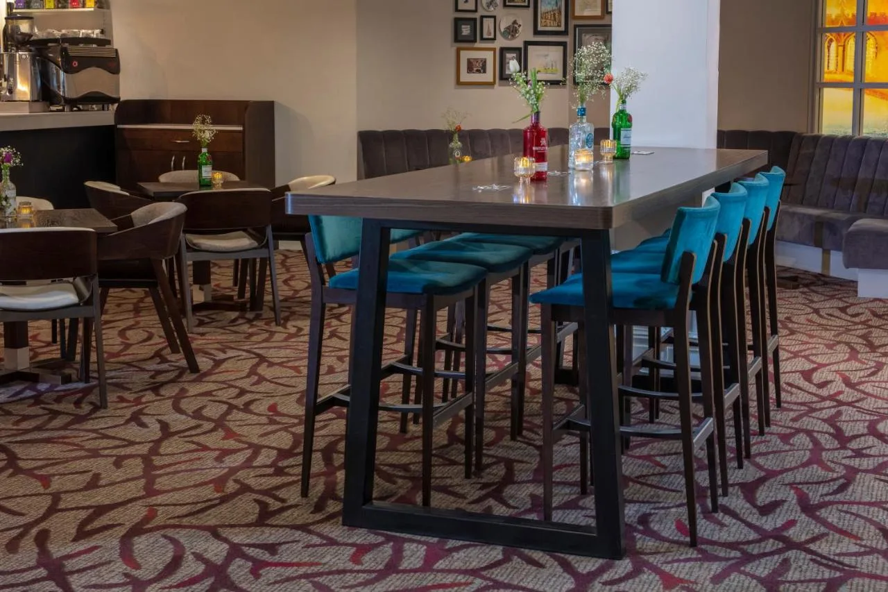 a dining room with a table and blue chairs at Cambridge Belfry Hotel & Spa in Cambourne